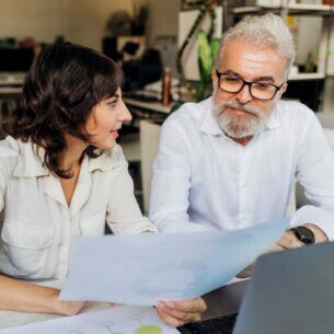 Zwei Personen schauen sich am Schreibtisch ein Diagramm an.
