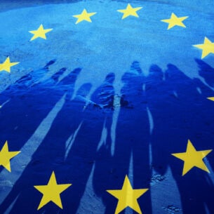 EU-Flagge, auf der der Schatten einer Gruppe Menschen zu sehen ist.