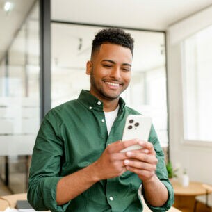 Eine Person sitzt mit einem iPhone in einem Büroumfeld.