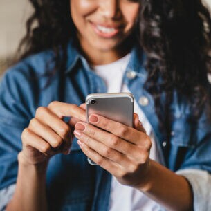 Eine Person tippt auf dem Smartphone, das sie in der Hand hält.