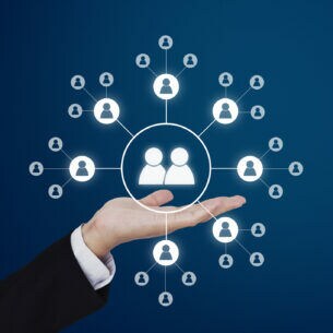 Um eine nach oben hin geöffnete Hand schweben weiße Kreise, die miteinander verbundene Personen darstellen.