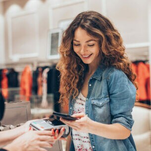 Eine Person bezahlt mit ihrem Smartphone in einem Bekleidungsgeschäft.