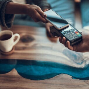 Nahaufnahme einer Hand, die mit einem Smartphone bezahlt.