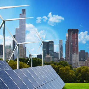 eine Reihe von Windräder und Solaranlagen. Im Hintergrund sind unterschiedliche Hochhäuser