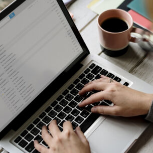 Eine Person tippt auf ihrem Laptop.