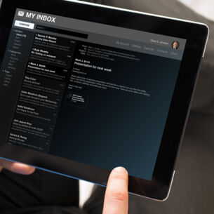 Ein Mann liest seine E-Mails auf einem Tablet.