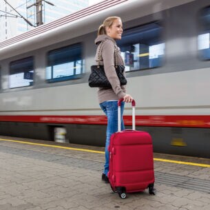 Bild: Person wartet mit Koffer am Bahnsteig