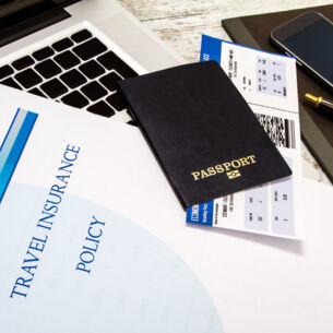 Blid: Reisepass Versicherungsvertrag auf Laptop liegend