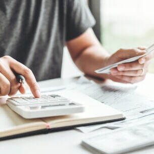 Artikelbild Person nutzt Taschenrechner und hat Dokumente vorliegen