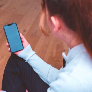 Artikelbild Person schaut auf iPhone 13