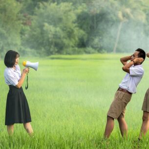 Bild: Kolleg:in schreit durch Mikrofon Kollge:innen an