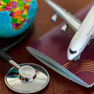 Global Healthcare and travel insurance concept. Passport Stethoscope, airplane and globe on wooden table