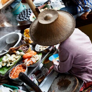 Frau verkauft Streetfood auf einem Boot in Thailand
