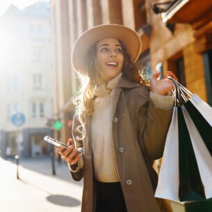 Frau hält lächelnd mehrere Shopping Tüten in der Hand