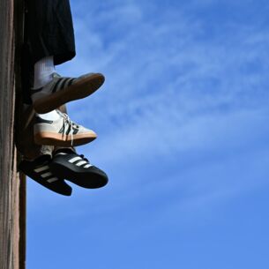 Ein junges Pärchen sitzt bei mildem, sonnigen Herbstwetter und blauem Himmel auf einer Mauer am Mainkai und lässt die Beine baumeln. (zu dpa: «Sneaker hoch im Kurs - Kein Ende des Booms in Sicht»)