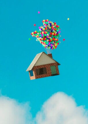 Haus fliegt mit Ballons durch blauen Himmel