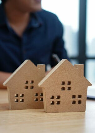 Ein Paar lässt sich beraten, vor ihnen stehen zwei kleine Modellhäuser