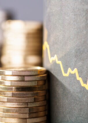 Münzstapel vor einer gezeichneten abfallenden Renditekurve