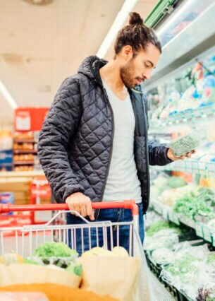 Ein junger Mann vor einem Gemüseregal in einem Supermarkt