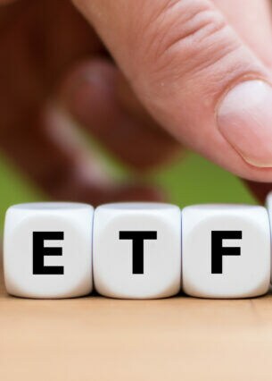 Drei Würfel mit den Buchstaben ETF und ein auf der Kippe gehaltener vierter Würfel mit Abwärts- und ein Aufwärtssymbol