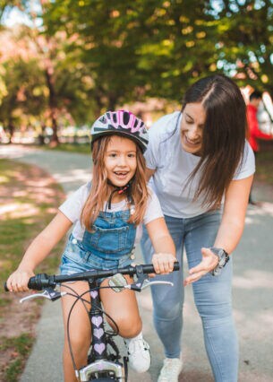 Mutter bringt ihrer Tochter das Fahrradfahren im Park bei