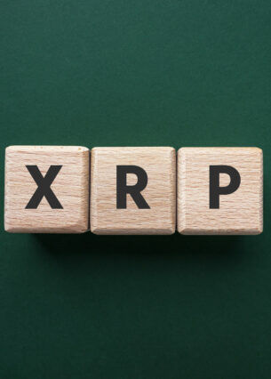 Drei Holzwürfel auf grünem Untergrund, die die Buchstaben XRP zeigen.