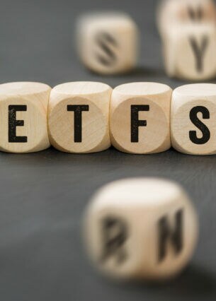 Mehrere Holzwürfel zeigen die Buchstaben ETFS sowie ein Fragezeichen und einen roten und grünen Pfeil