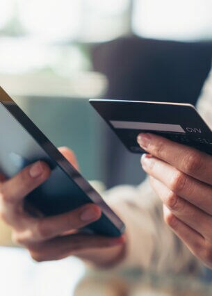 Eine Person hält ein Smartphone und eine Bankkarte in den Händen.