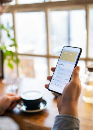 Eine Person blickt auf ihr Handydisplay, auf der eine Konto-App zu erkennen ist