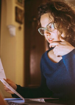 Eine junge Frau sitzt am Tisch und liest Dokumente