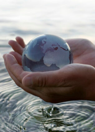 Ein Modell einer Weltkugel, die in zwei Händen gehalten wird, die über Wasser gehalten werden