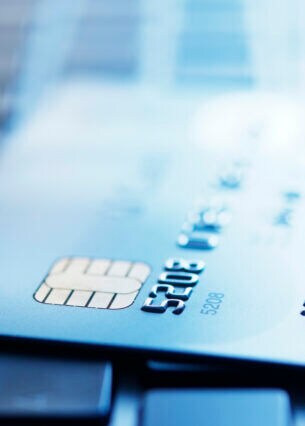 Blau getöntes Foto einer Kreditkarte, die auf der Tastatur eines Laptops liegt und deren Kreditkartennummer erkennbar ist.