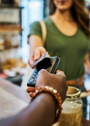 Eine Frau hält in einem Einkaufladen eine Karte an ein Kartenlesegerät