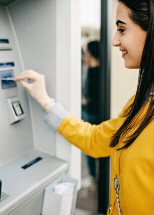 Eine Frau steckt eine Karte in den Eingabeschlitz eines Geldautomaten