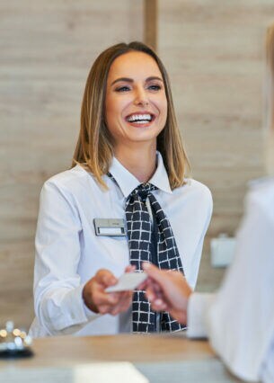 Eine Person an einer Rezeption nimmt von einer anderen Person eine Kreditkarte entgegen.