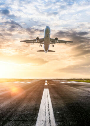 Ein Flugzeug startet bei Sonnenuntergang von der Landebahn.