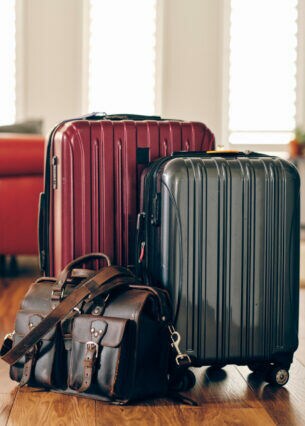 Zwei Koffer und eine Reisetasche stehen vor einem roten Sofa