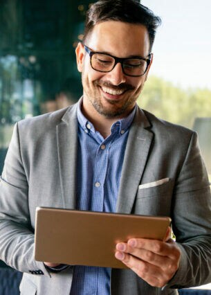Eine Person tippt lächelnd auf einem Tablet.