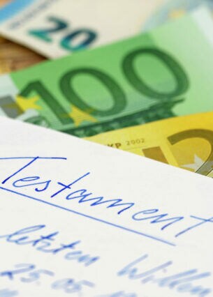 Auf einem Blatt steht handschriftlich geschrieben "Testament", darunter liegen mehrere Euroscheine.