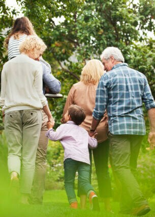 Eine Familie in der Rückansicht, die durch einen Garten spaziert.
