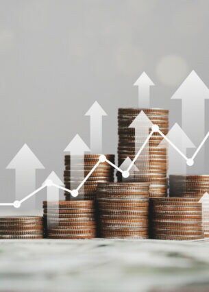 Mehrere Münstapel auf Geldscheinen, darüber sind ein digitaler Graph sowie Pfeile gelegt.