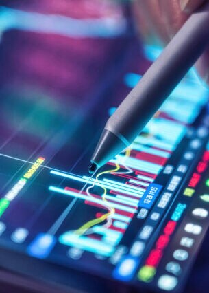 Nahaufnahme eines Stifts, der auf einem Tablet auf einen Aktienkurs zeigt.