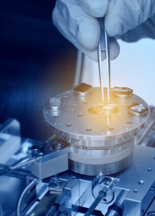 aNahaufnahme einer Hand, die mit einer Pinzette einen Nanochip platziert.