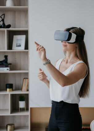 Eine Person steht in einem Wohnzimmer und trägt eine Virtual-Reality-Brille.