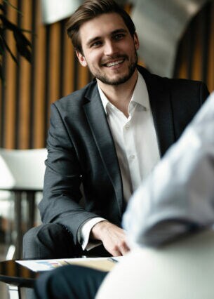 Zwei Personen in Businesskleidung sitzen sich an einem Tisch gegenüber.