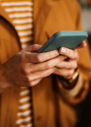 Eine Person hält mit beiden Händen ein Smartphone auf Brusthöhe.