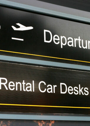 Wegweiser am Flughafen, der zu den Autovermietungen zeigt.