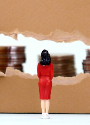 Eine Miniatur einer Frau vor einem aufgerissenen Stück Karton, hinter dem sich mehrere Stapel Münzen befinden.