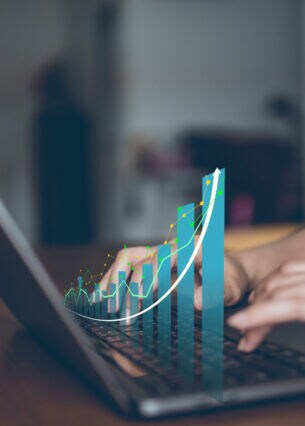 Eine Person sitzt am Notebook. Über das Notebook ist ein Balkendiagramm mit steigenden Balken gelegt.
