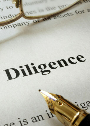 Ein Dokument, das mit Due Diligence überschrieben ist und auf dem ein Füllfederhalter und eine Brille liegen.